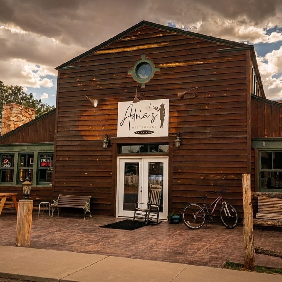 Adria's Restaurant, a rustic wooden building with outdoor picnic tables, under a cloudy sky.